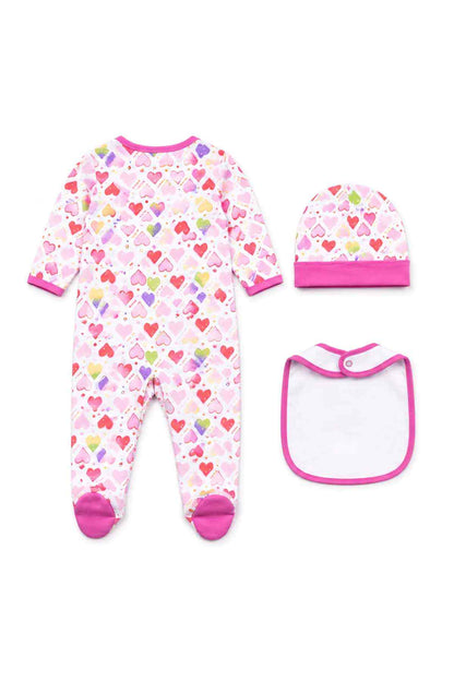 Flat lay: pink heart-print footed sleeper, matching cap, and bib with pink trim