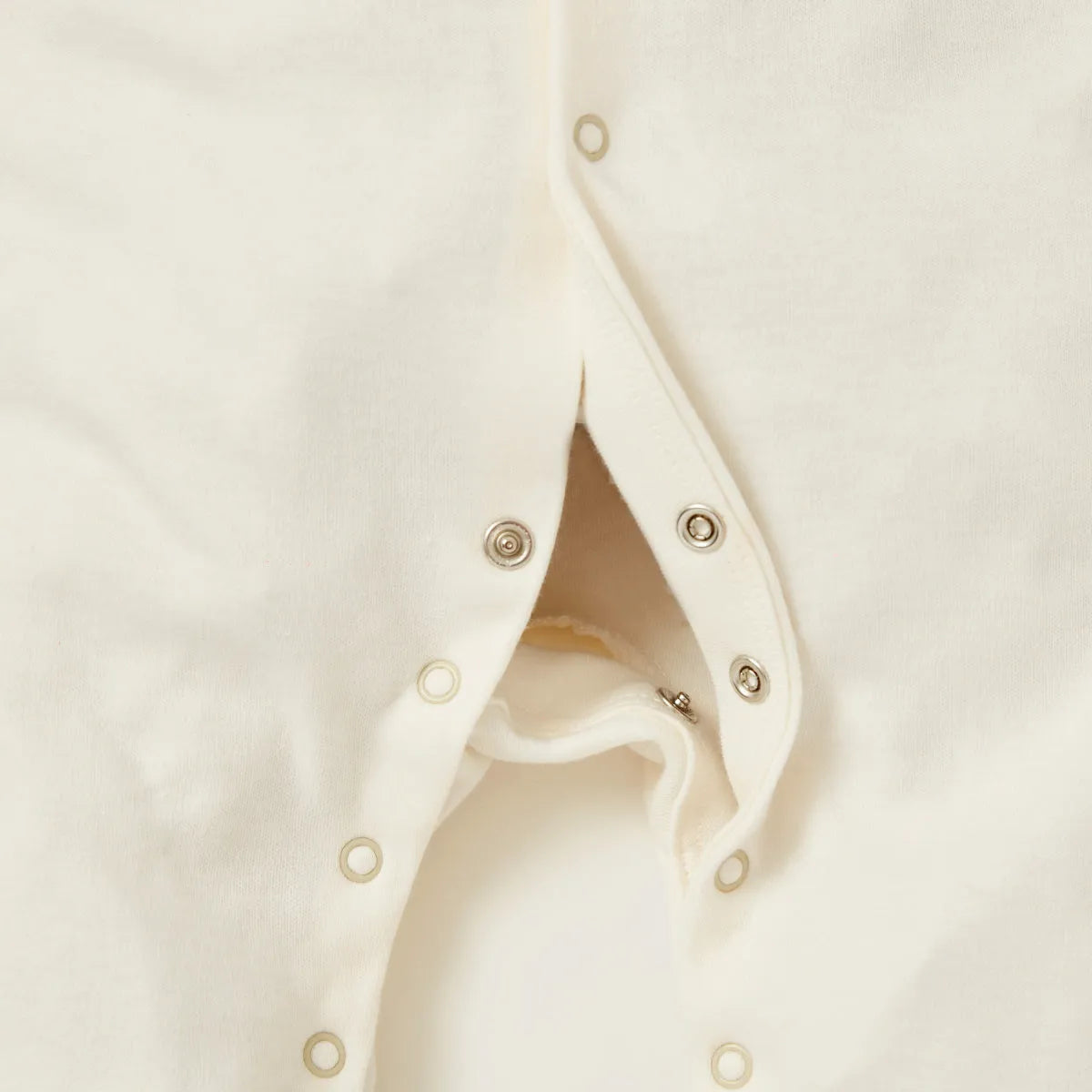 Off-white baby romper close-up of snap buttons along the front opening