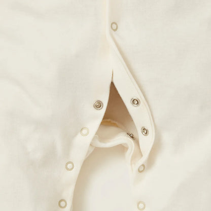 Off-white baby romper close-up of snap buttons along the front opening