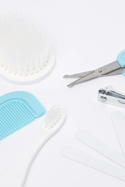 Baby grooming tool set close-up: blue comb, white brush, and metal scissors