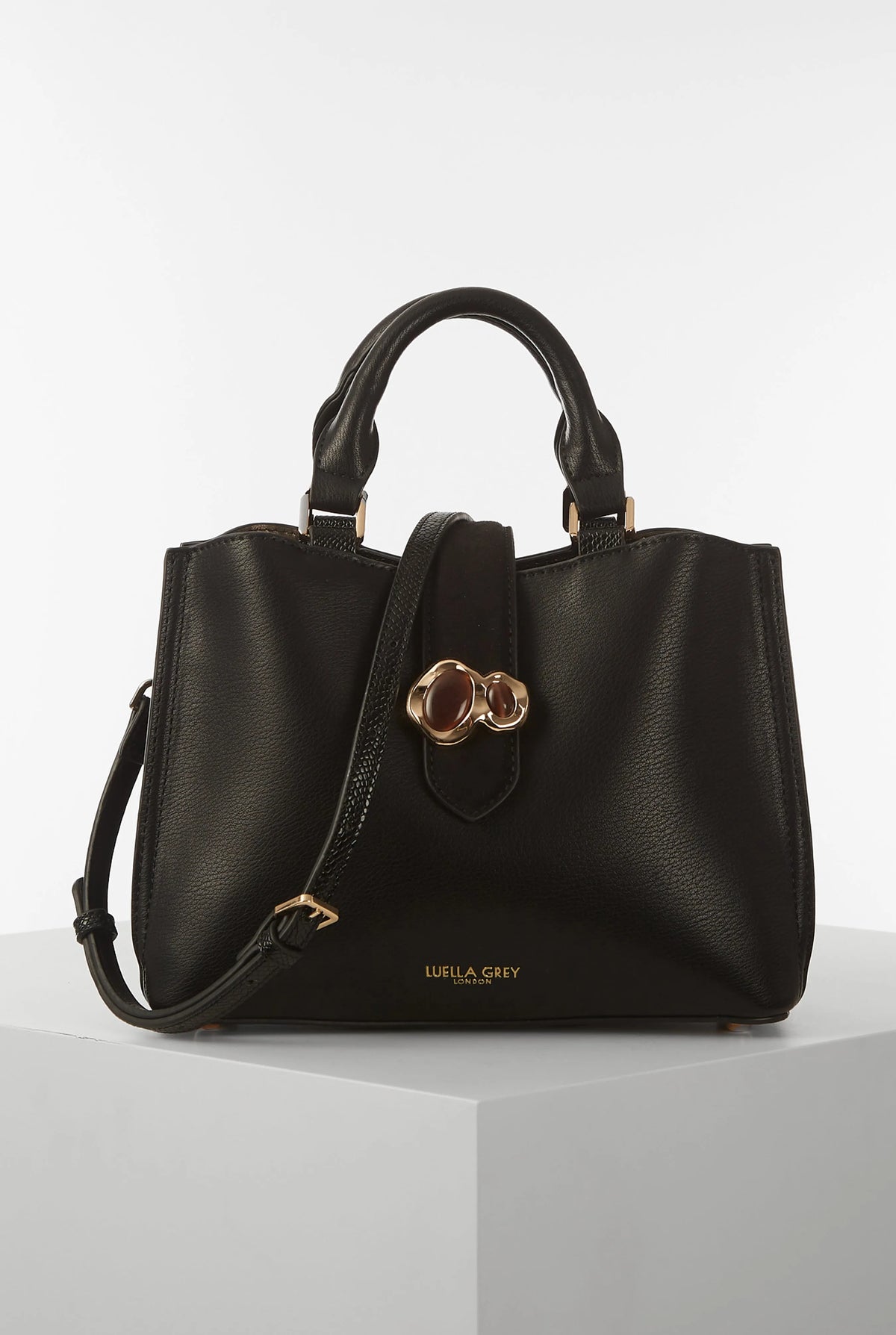 Black handbag with top handles, front clover hardware, and zip pocket