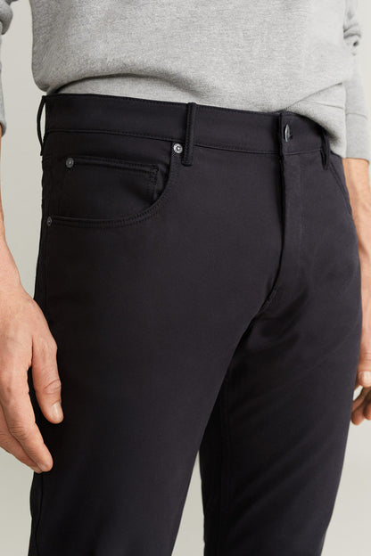 Black pants front detail: waistband, button, and coin pocket with stitching.