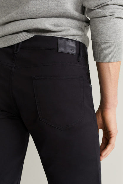 Black pants close-up: waistband label and back pocket with stitched seams.