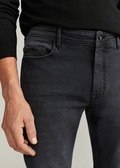 Close-up of dark grey denim jeans: contrast stitching, zip fly, side pocket