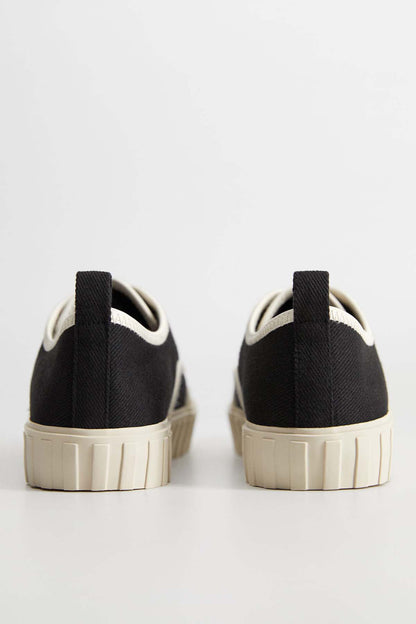 Back view of black and cream lace-up sneakers with platform sole