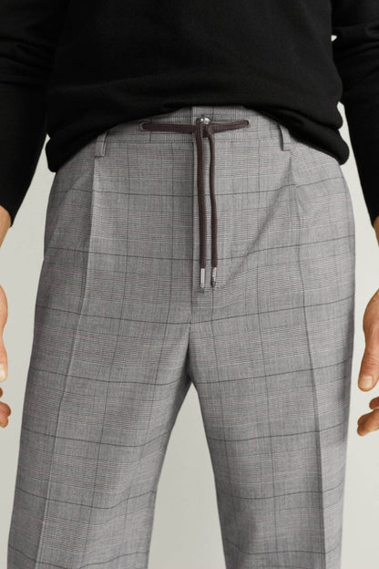 Men's light grey check trousers showing drawstring and belt loops at waistband