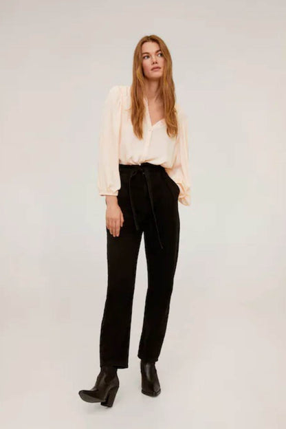 Light pink peasant blouse with V-neck; black belted trousers with boots