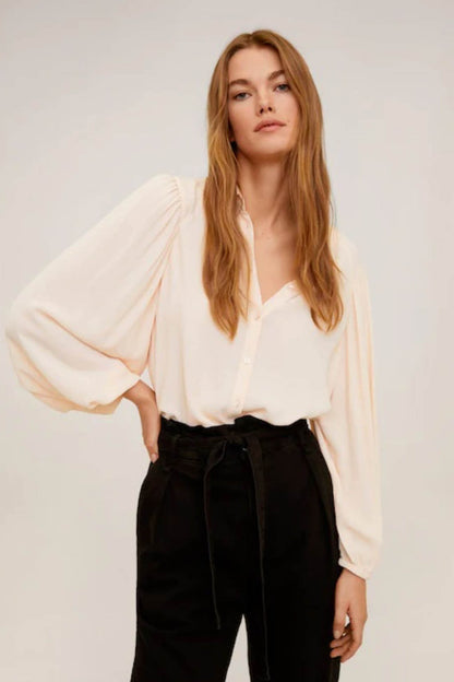 Light pink peasant blouse with puff sleeves and button front, paired with black belted pants