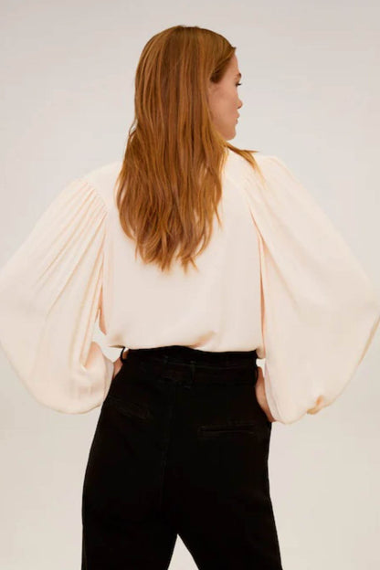 Light pink peasant blouse with puff sleeves; black belted trousers shown from side
