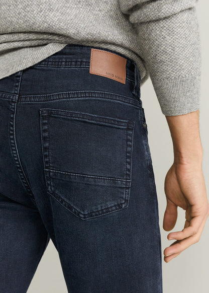 Dark blue jeans back pocket with tan logo patch and stitched seams