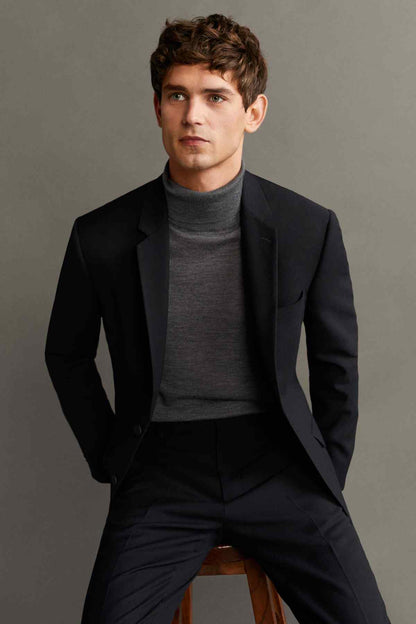 Men's black suit jacket worn with dark trousers; front view