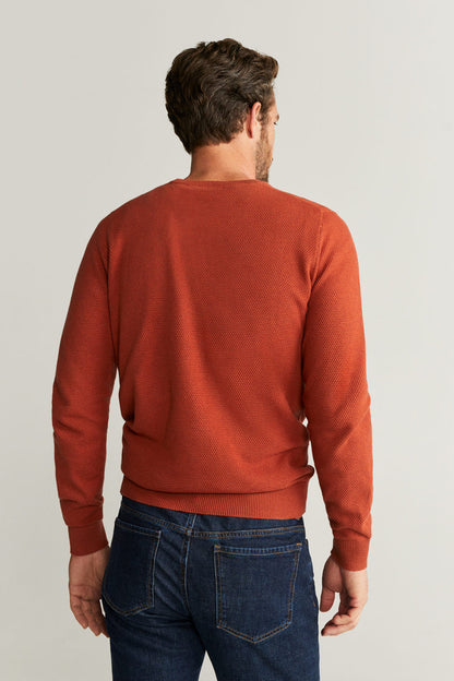 Men's rust-orange crewneck sweater shown from the back with ribbed cuffs
