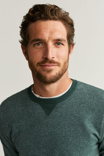 Green crewneck knit sweater close-up with ribbed collar and cuffs