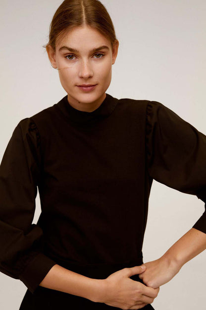 Black high-neck jumpsuit close-up with long puff sleeves and gathered shoulder detail