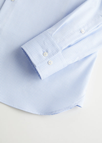 Light blue dress shirt cuff with button closure and fine check pattern