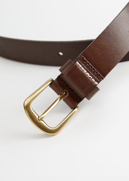 Brown leather belt with gold buckle close-up and contrast stitching