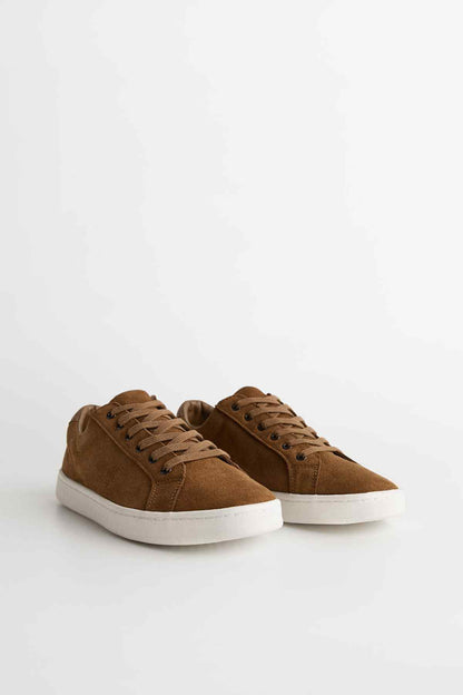 Pair of brown suede lace-up sneakers with white soles, side view