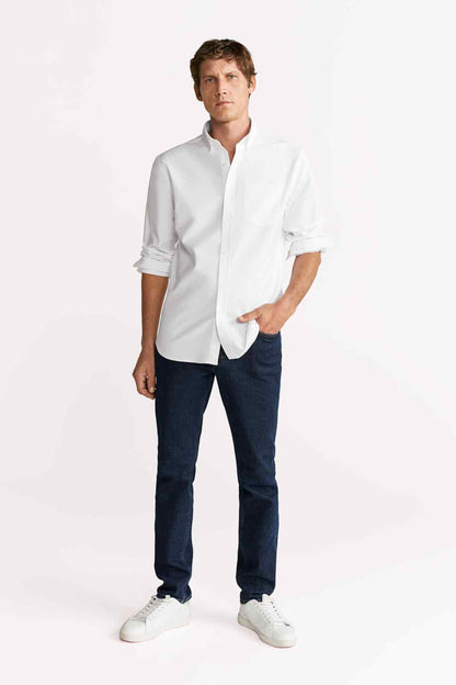 Men's white button-up shirt with pointed collar and dark jeans, standing full length