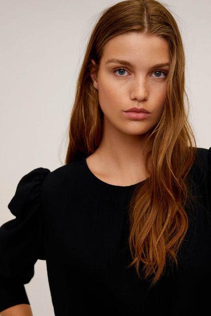 Black blouse close-up: round neckline and puffed shoulders