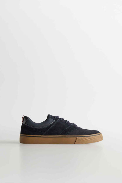 Navy lace-up sneaker with gum rubber sole, low-profile design.
