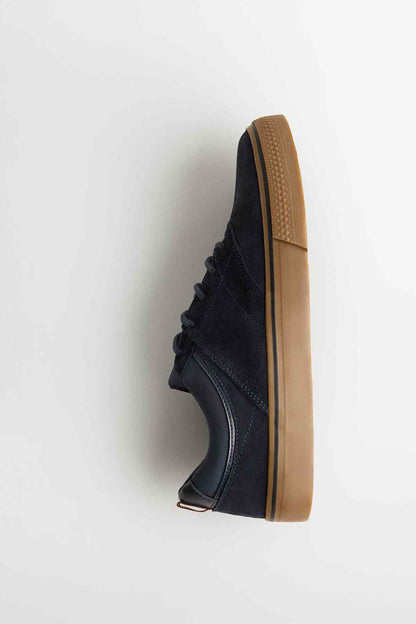 Navy low-top sneaker side profile with lace-up closure and gum rubber outsole.