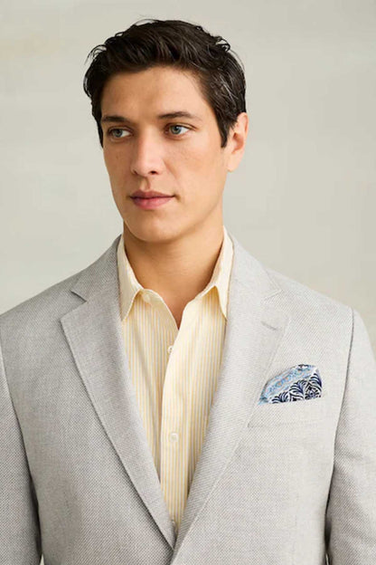 Men's light grey blazer with notched lapels and blue patterned pocket square
