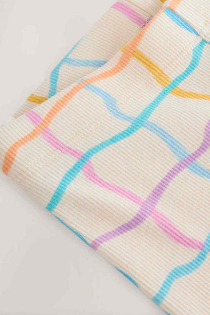 Close-up of white leggings fabric with colorful rainbow grid lines and pastel stripes
