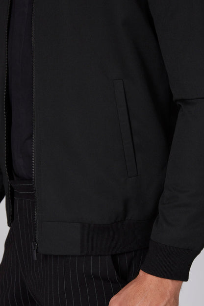 Black jacket close-up: zip front, chest pocket, ribbed hem