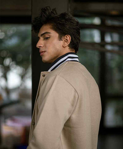 Men's tan fitted bomber jacket, striped ribbed collar, side profile close-up