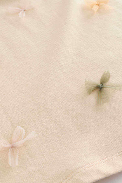 Ecru T-shirt fabric close-up with embroidered butterfly accents