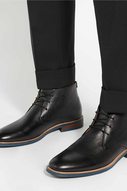 Black lace-up ankle boots with low blue-brown sole worn with dark trousers