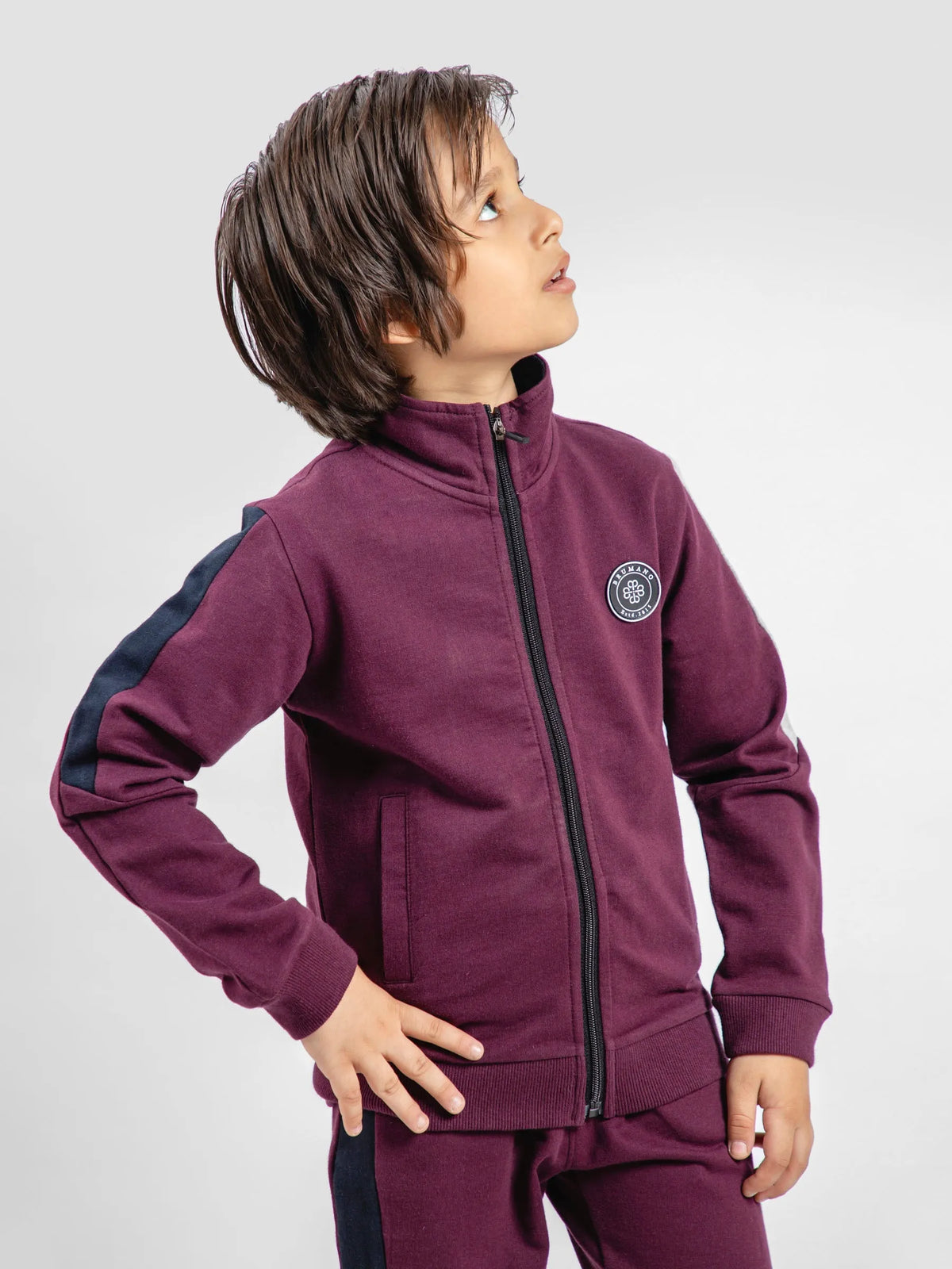 Burgundy kids zip-up tracksuit jacket with chest badge, side profile