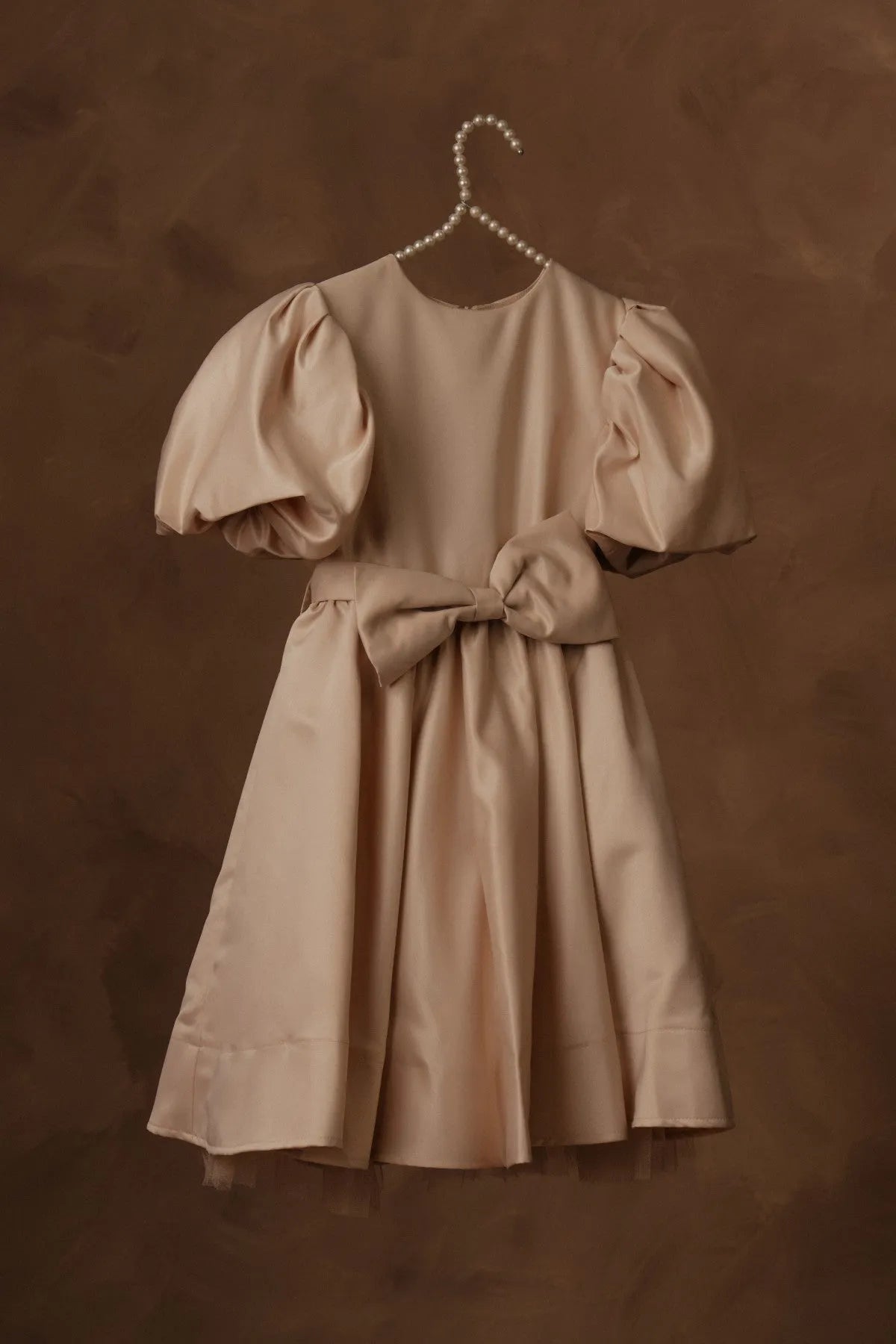 Beige puff-sleeve dress with bow belt and gathered skirt on hanger