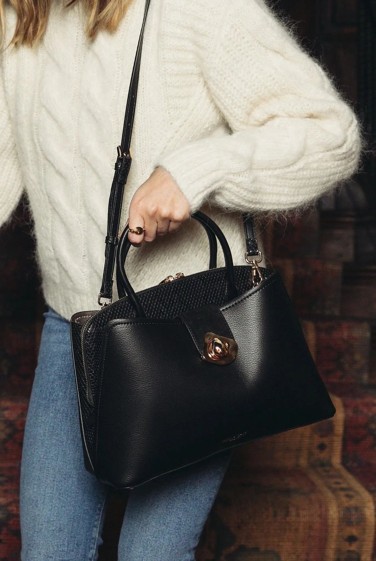Black handbag with top handles and shoulder strap, gold-tone turn-lock clasp
