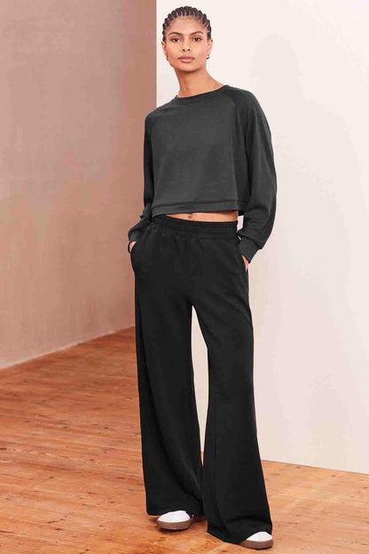 Charcoal grey wide-leg trousers with button details at the sides