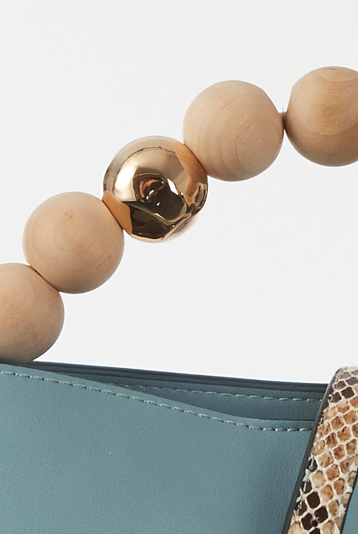 Wooden bead handle with gold clasp on teal handbag edge and leopard strap