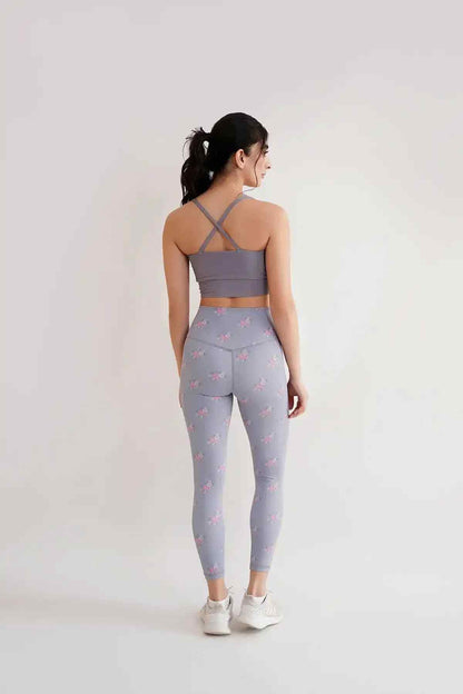 Back view: grey racerback sports bra with floral leggings, full length