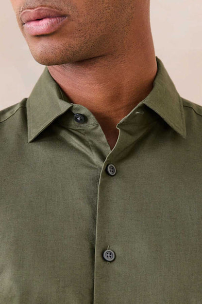 Green button-up shirt collar and dark buttons close-up