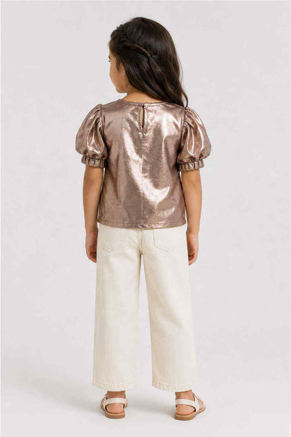 Metallic gold top with puff sleeves on child's back, paired with cream pants