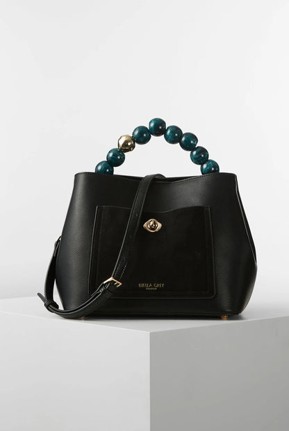 Black leather-look handbag with teal beaded handle, front pocket, and gold clasp