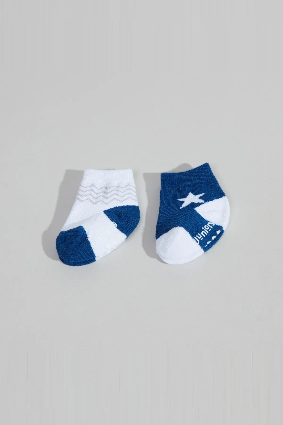 Pair of baby socks: one white with blue trim and plane print, one dark blue.