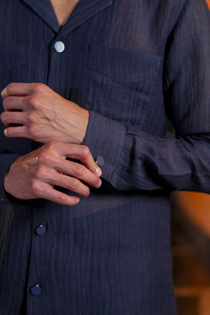 Men's dark blue kurta shirt with circular buttons and long sleeves, close-up hands