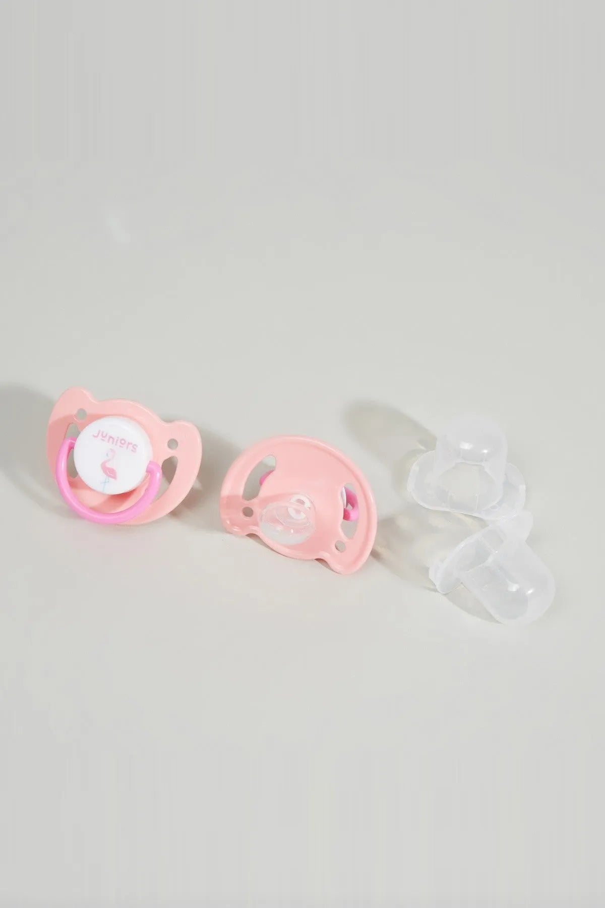 Three baby pacifiers: pink shields and one clear shield, orthodontic nipples