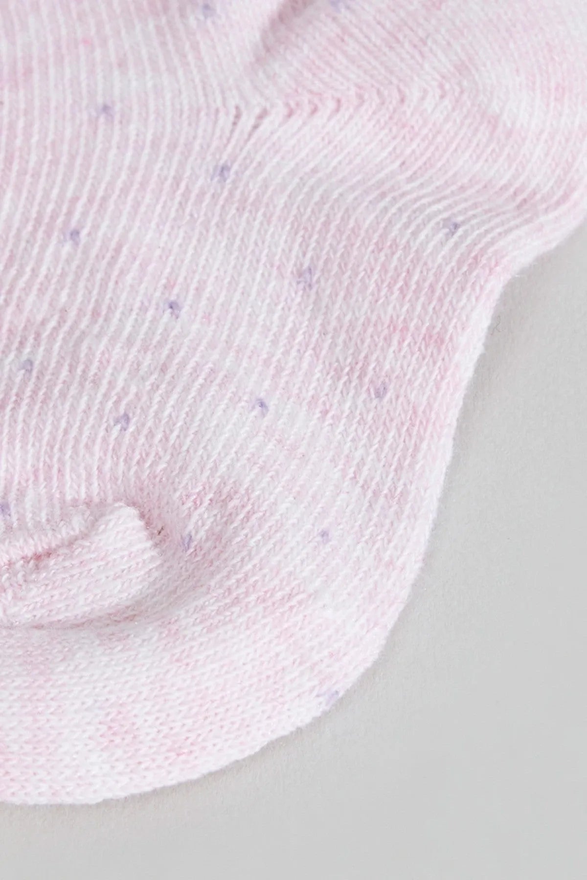 Close-up of pink baby sock knit with ribbed cuff and heel