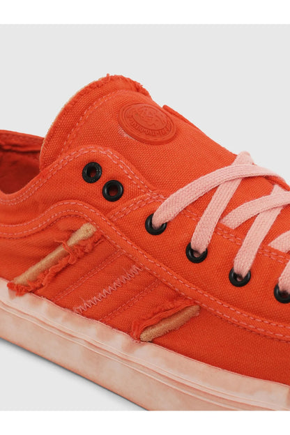 Orange canvas sneakers close-up: lace eyelets, stitched panel, and rubber toe cap