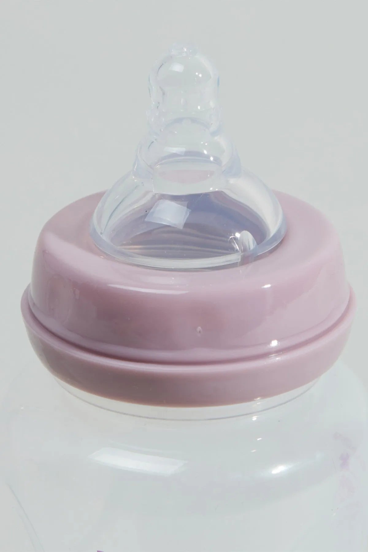Clear baby bottle with pink screw-on lid and drinking spout, close-up front view