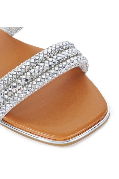 Close-up of silver rhinestone slide sandal strap with tan footbed and flat sole