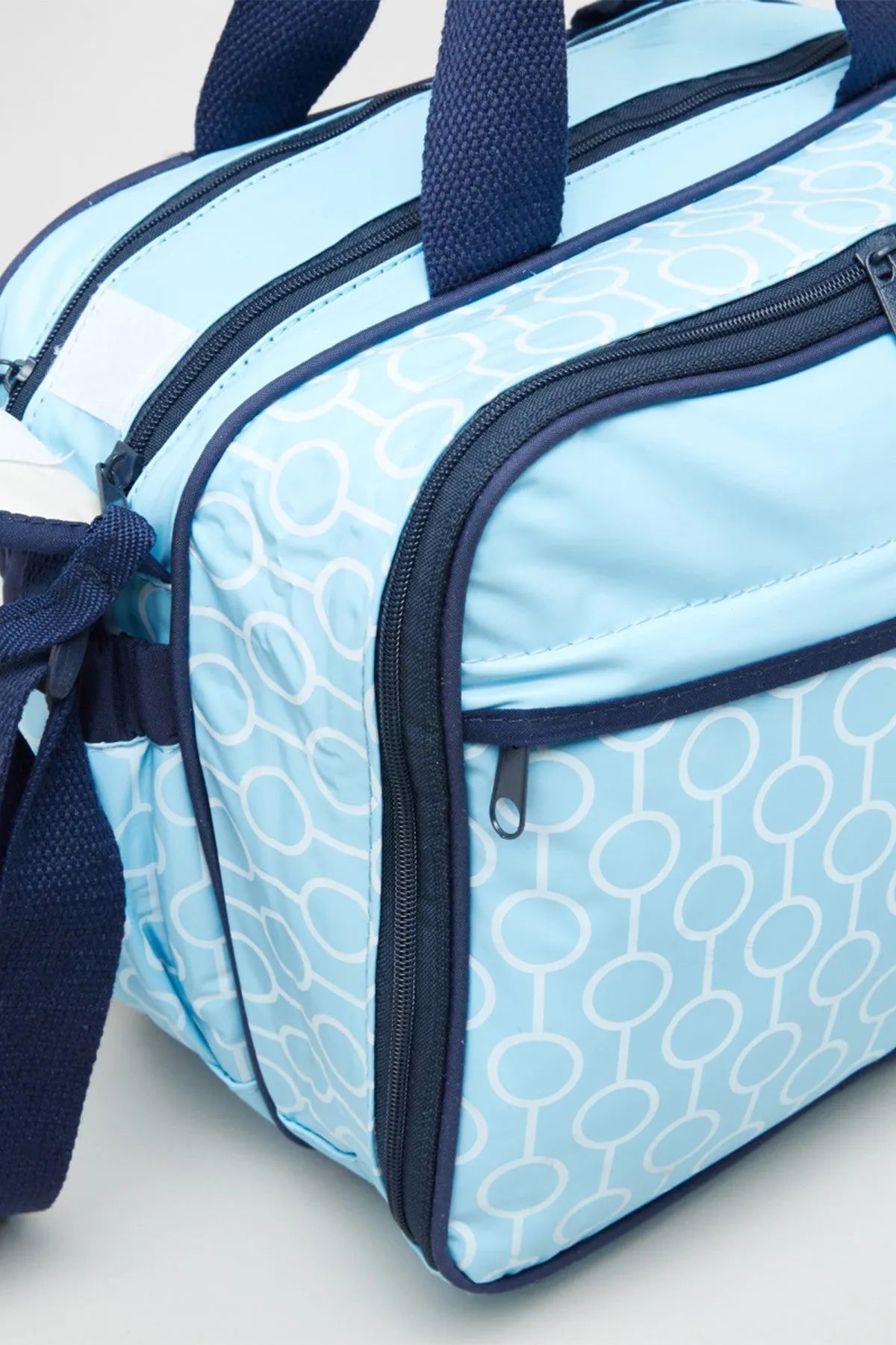 Blue patterned baby tote bag with dark trim, front zipper pocket, and handle straps
