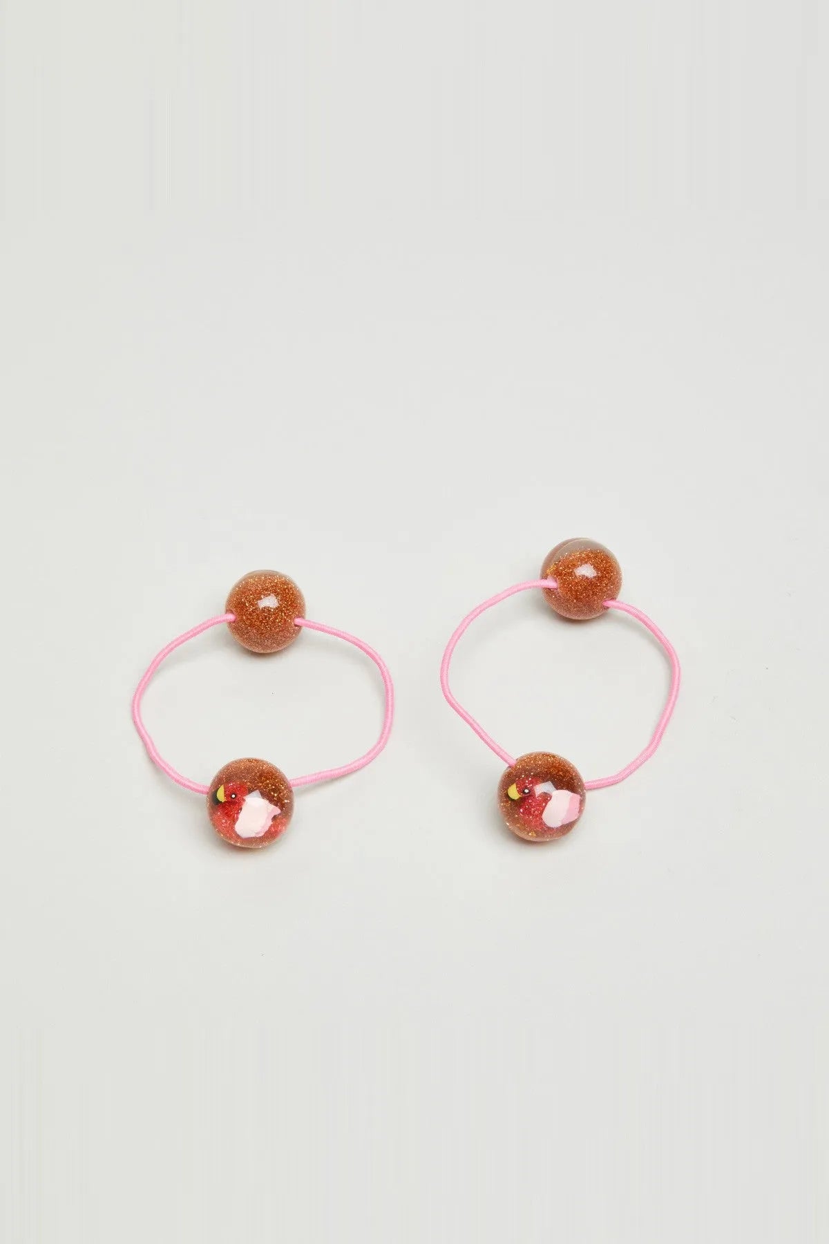 Two pink hair ties with glitter amber bead charms, round elastic loops