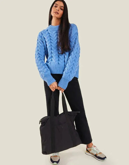 Black travel tote bag held by model, wide base and long top handles